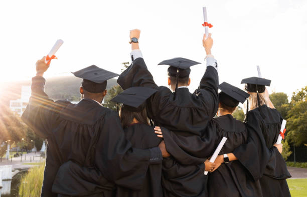Grupo de formandos abraçados comemorando com diplomas erguidos